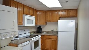 Eine Küche mit Holzausstattung, einem weißen Kühlschrank, einer Mikrowelle, einem Herd und einem Spülbecken.