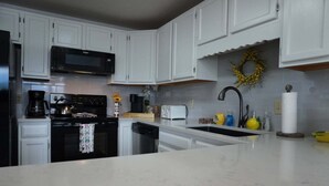 A kitchen with white cabinets, a microwave, a stove, a sink, and a decorative wreath. - Smoky Mountains 711 3BD Condo with All Round Private Balcony by RedAwning (Pigeon Forge)