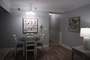 A dining area with a round table, four chairs, a chandelier, and two wall-mounted lamps. - Smoky Mountains 304 2BD Condo with Private Balcony and Fireplace by RedAwning (Pigeon Forge)