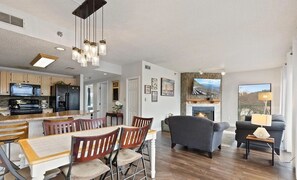 A spacious living area with a dining table, chairs, a fireplace, and a sofa. - Smoky Mountains 610 3BD Condo with Fireplace and Jacuzzi Tub by RedAwning (Pigeon Forge)