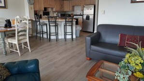 A living room with a sofa, a coffee table, and a kitchen area with wooden cabinets and a refrigerator. - City View 410 3BD Condo with Private Balcony by RedAwning (Pigeon Forge)