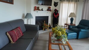 A living room with a sofa, armchair, fireplace, bear decorations, and a television. - City View 410 3BD Condo with Private Balcony by RedAwning (Pigeon Forge)
