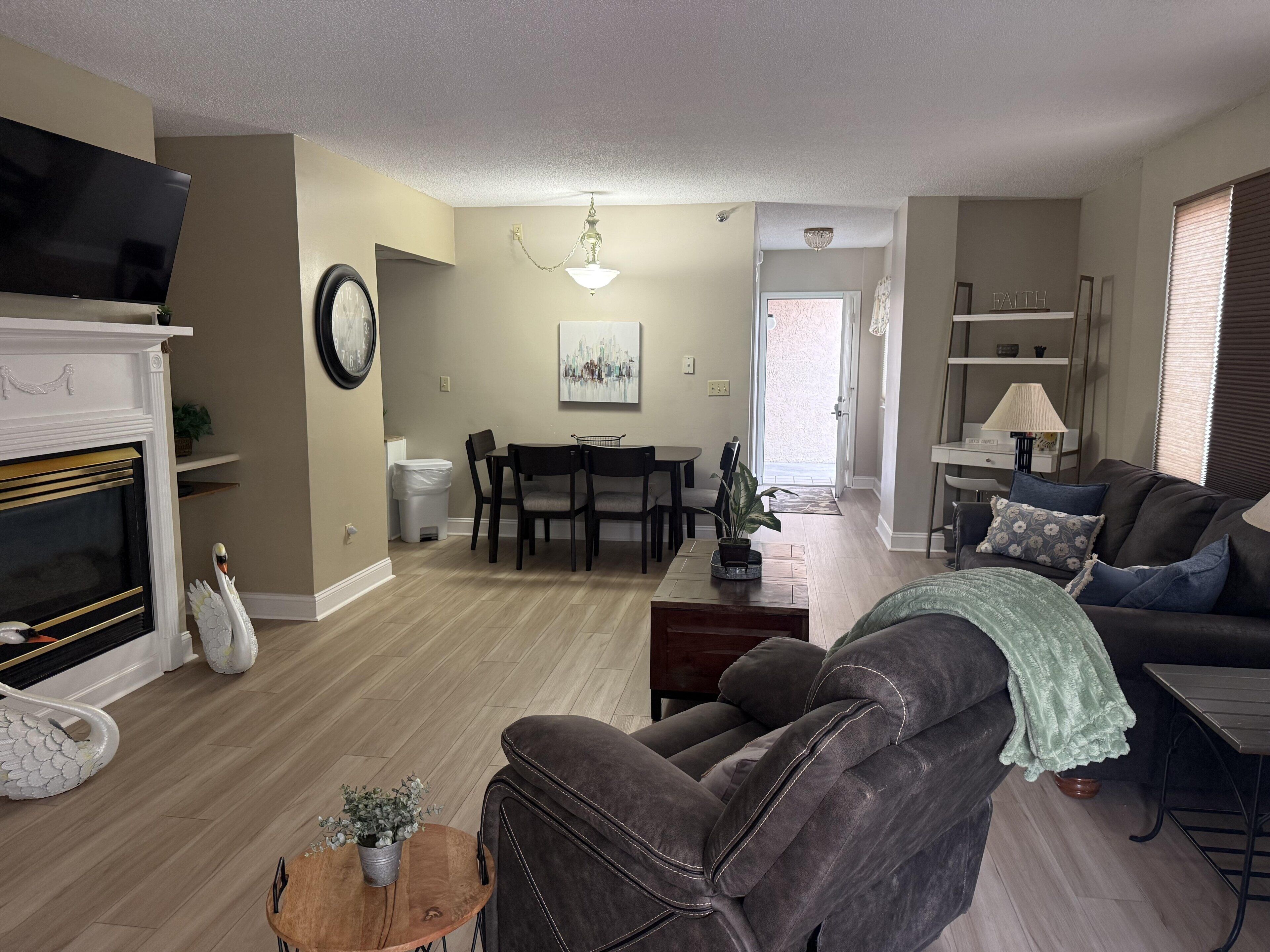 A living room with a fireplace, a sofa, a dining table with chairs, and a television.