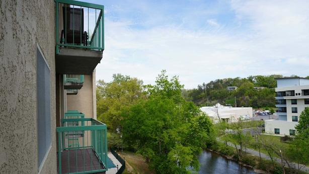 A multi-story building with balconies, a river, and surrounding greenery. - Little Pigeon River 508 2BD Condo with Fireplace and Jacuzzi Tub by RedAwning (Pigeon Forge)