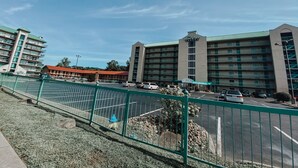 A hotel with multiple floors, a red roof, and a sign reading "River Place Condos". - Little Pigeon River 508 2BD Condo with Fireplace and Jacuzzi Tub by RedAwning (Pigeon Forge)