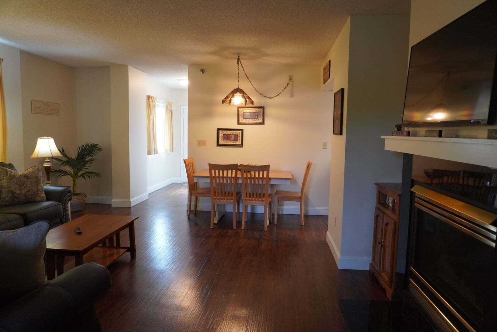 A living room with a dining table, chairs, a sofa, a lamp, a fireplace, and a television.