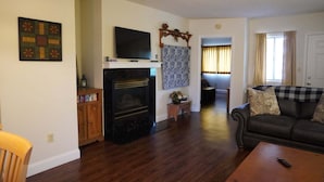 A living room with a fireplace, a sofa, a television, and a patterned wall hanging. - Little Pigeon River 508 2BD Condo with Fireplace and Jacuzzi Tub by RedAwning (Pigeon Forge)