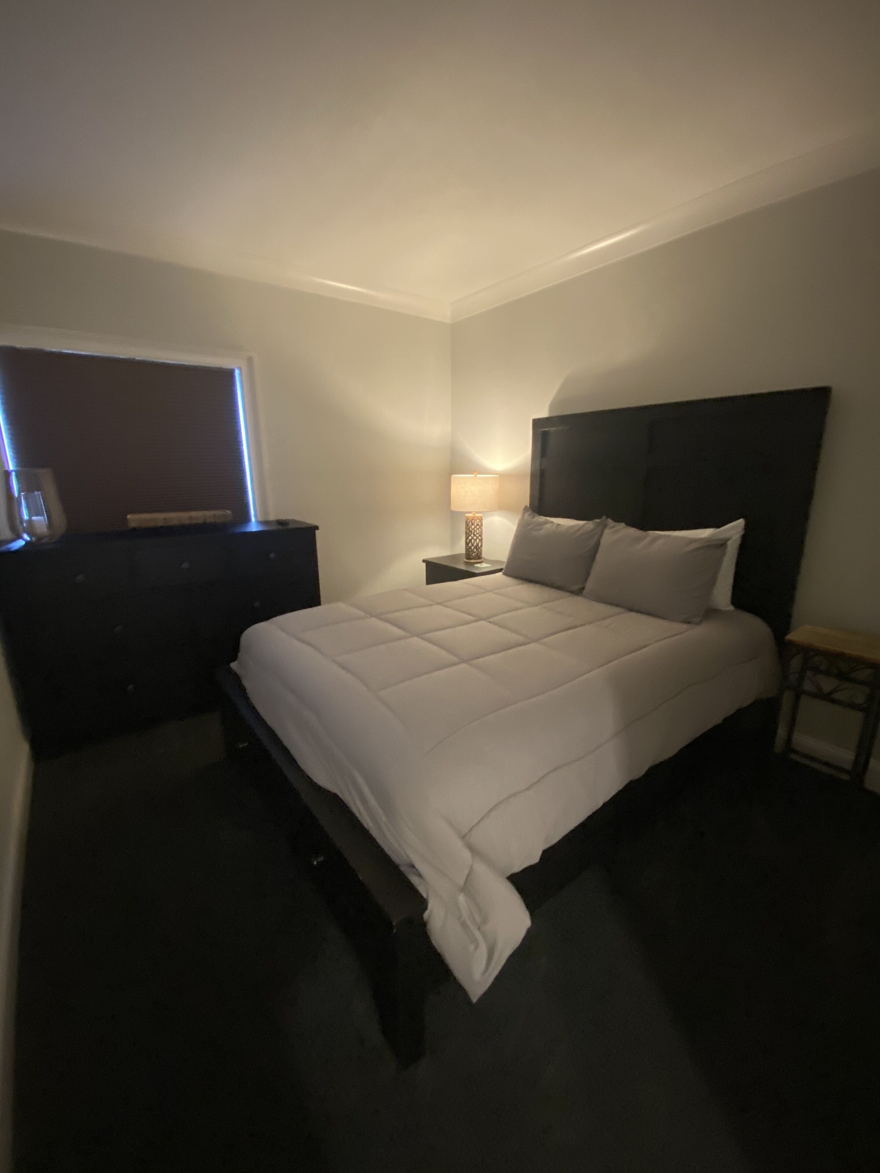 A neatly arranged bedroom with a bed, bedside table, and a nightstand.