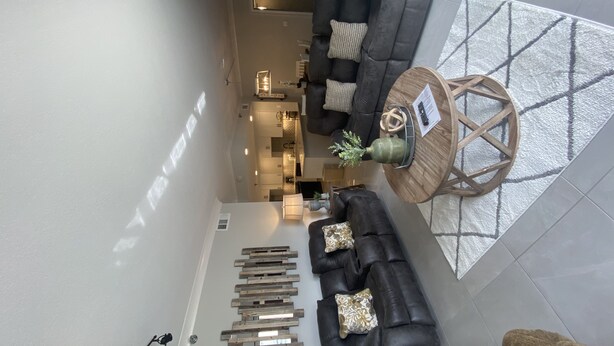 A modern living room with two dark leather sofas, a wooden coffee table with decorative items, a kitchen in the background, and a large mirror on the wall. - 111 3bd 3 Bedroom Condo by RedAwning (Pigeon Forge)