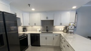 A modern kitchen with white cabinets, a black refrigerator, and a herringbone backsplash. - 111 3bd 3 Bedroom Condo by RedAwning (Pigeon Forge)
