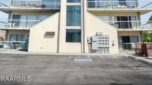 A multi-story building with balconies, a central vertical feature, and a parking area with a handicapped parking sign. - 111 3bd 3 Bedroom Condo by RedAwning (Pigeon Forge)