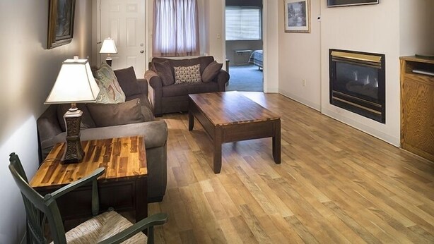 A living room with a sofa, a wooden coffee table, a lamp, and a fireplace. - Little Pigeon River 602 2BD Condo with Private Balcony by RedAwning (Pigeon Forge)