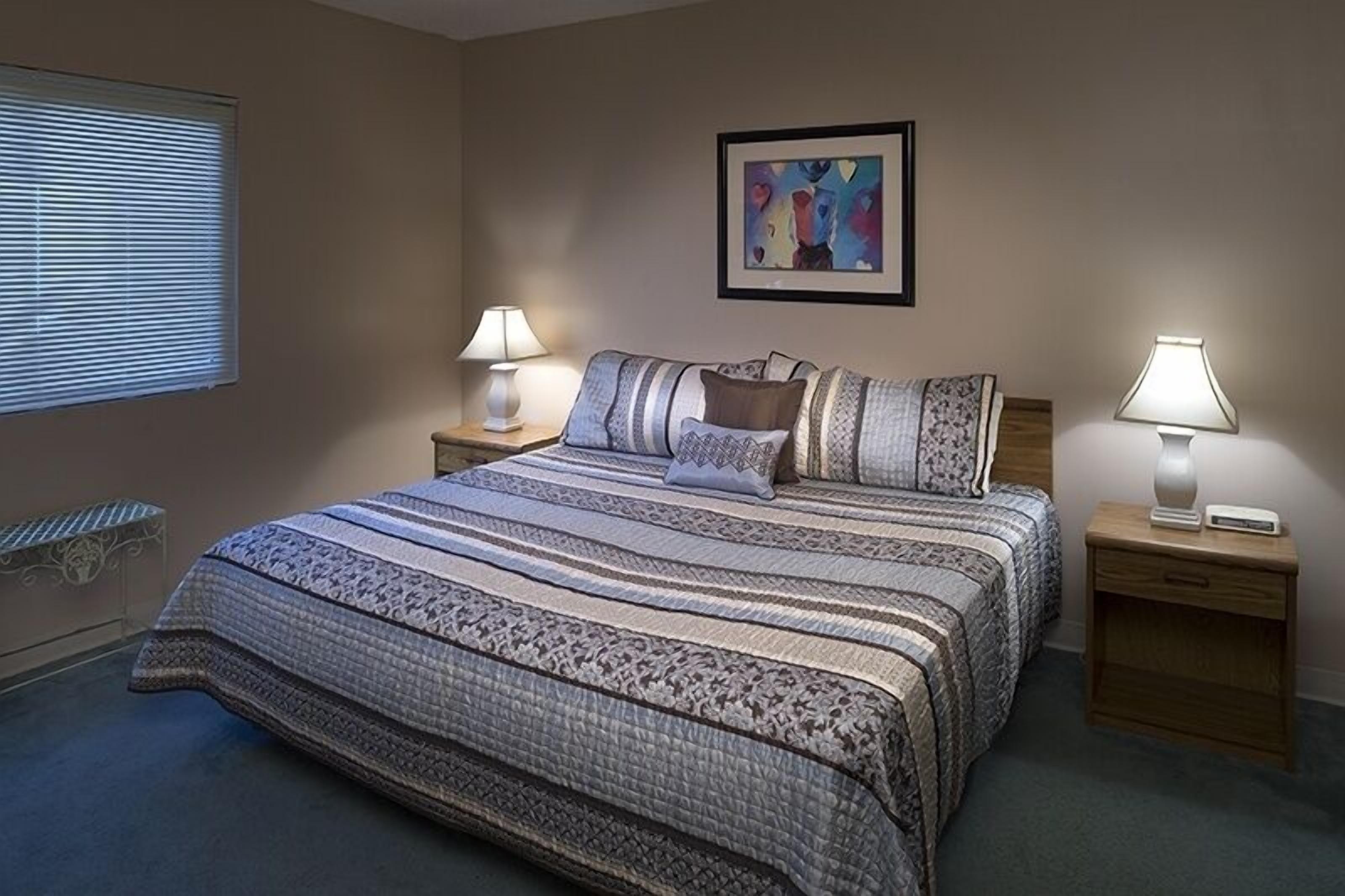 Una camera da letto con un letto grande, due comodini con lampade, una panca e un quadro astratto appeso alla parete.