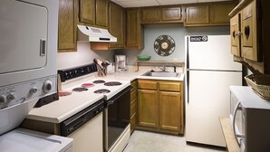 A compact kitchen with wooden cabinets, a white stove, a sink, and a refrigerator. - Little Pigeon River 602 2BD Condo with Private Balcony by RedAwning (Pigeon Forge)