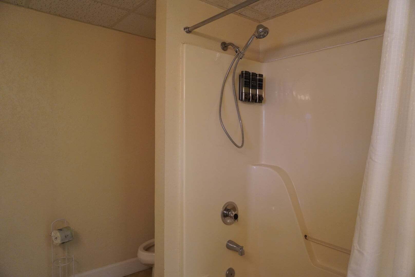 A bathroom with a shower, toilet, and a towel rack.