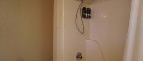 A bathroom with a shower, toilet, and a towel rack.