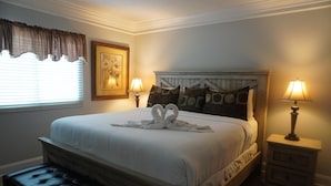 A bedroom with a bed, two bedside tables, a bench, a window with curtains, and a wall-mounted picture. - Smoky Mountains 101 2BD Condo with Fireplace and Private Balcony by RedAwning (Pigeon Forge)