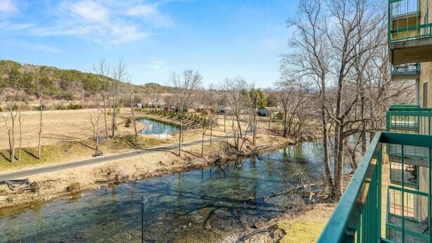 A river with a clear view of a building with a green balcony. - Smoky Mountains 101 2BD Condo with Fireplace and Private Balcony by RedAwning (Pigeon Forge)