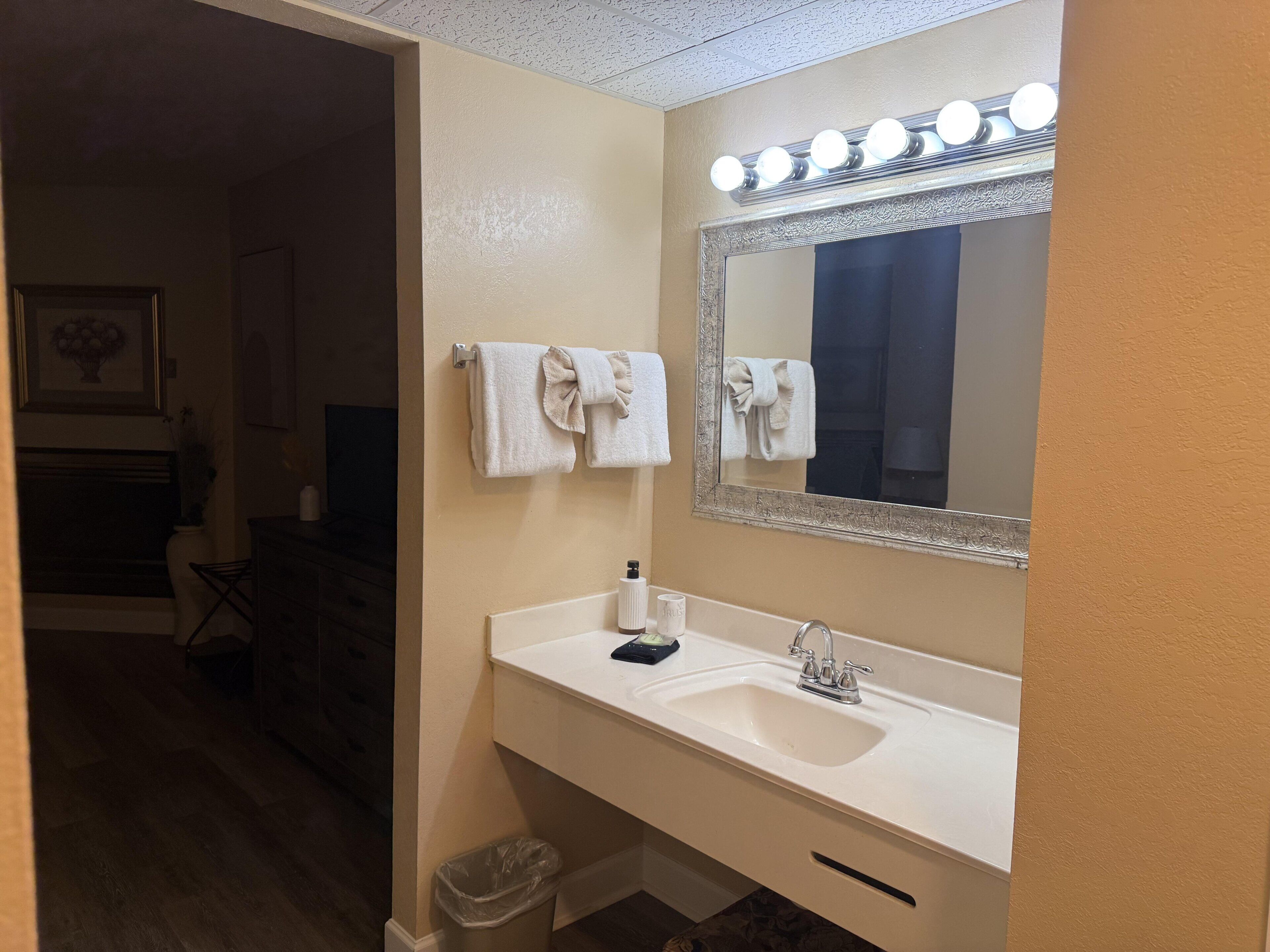 A bathroom with a sink, mirror, and lights.