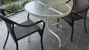 A balcony with a round glass table and two wicker chairs, overlooking a green landscape. - 609 1bd 1 Bedroom Condo by RedAwning (Pigeon Forge)