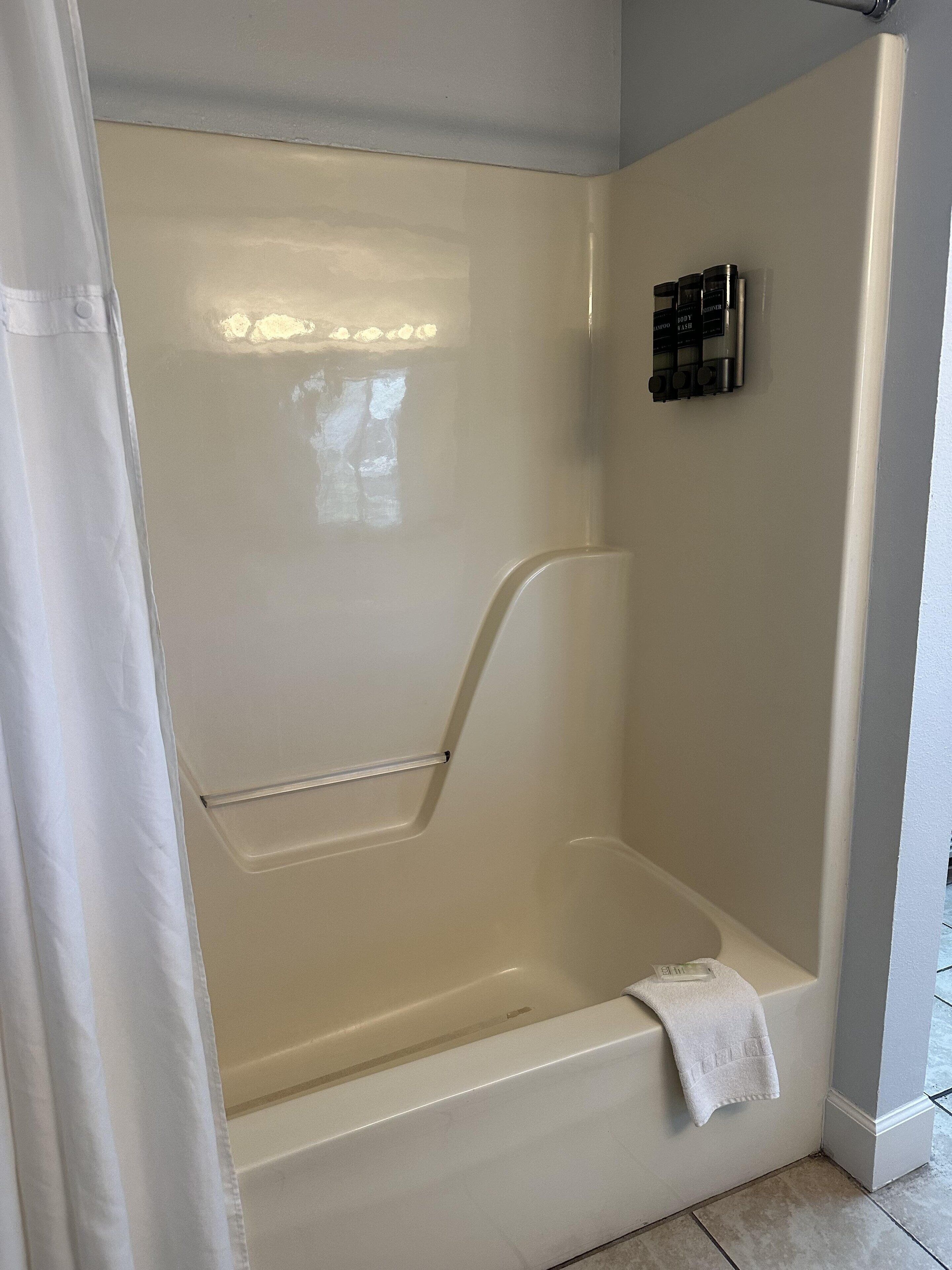 Eine Badewanne mit Duschvorhang, Handtuch und Bedienelementen an der Wand.