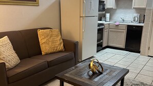 A living room with a brown sofa, a coffee table, and a rug. There is a kitchen area with cabinets and appliances. - 409 1bd 1 Bedroom Condo by RedAwning (Pigeon Forge)