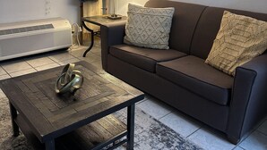 A living room with a brown sofa, a wooden coffee table, a lamp, a radiator, and a framed picture on the wall. - 409 1bd 1 Bedroom Condo by RedAwning (Pigeon Forge)