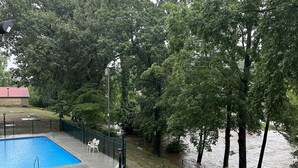 Ein Swimmingpool mit Liegestühlen, umgeben von einem Zaun und Bäumen.