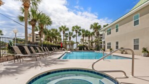 A swimming pool with lounge chairs and palm trees, surrounded by a building with balconies. - Crystal Beach. Caribbean Dunes. Completely Renovated. Corner Unit. Gulf View.  (Destin)