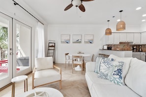 Un salon moderne avec un canapé blanc, une table à manger avec des chaises et un ventilateur de plafond.