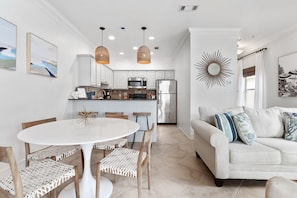 Une cuisine moderne avec des meubles blancs, un îlot central et des luminaires suspendus.