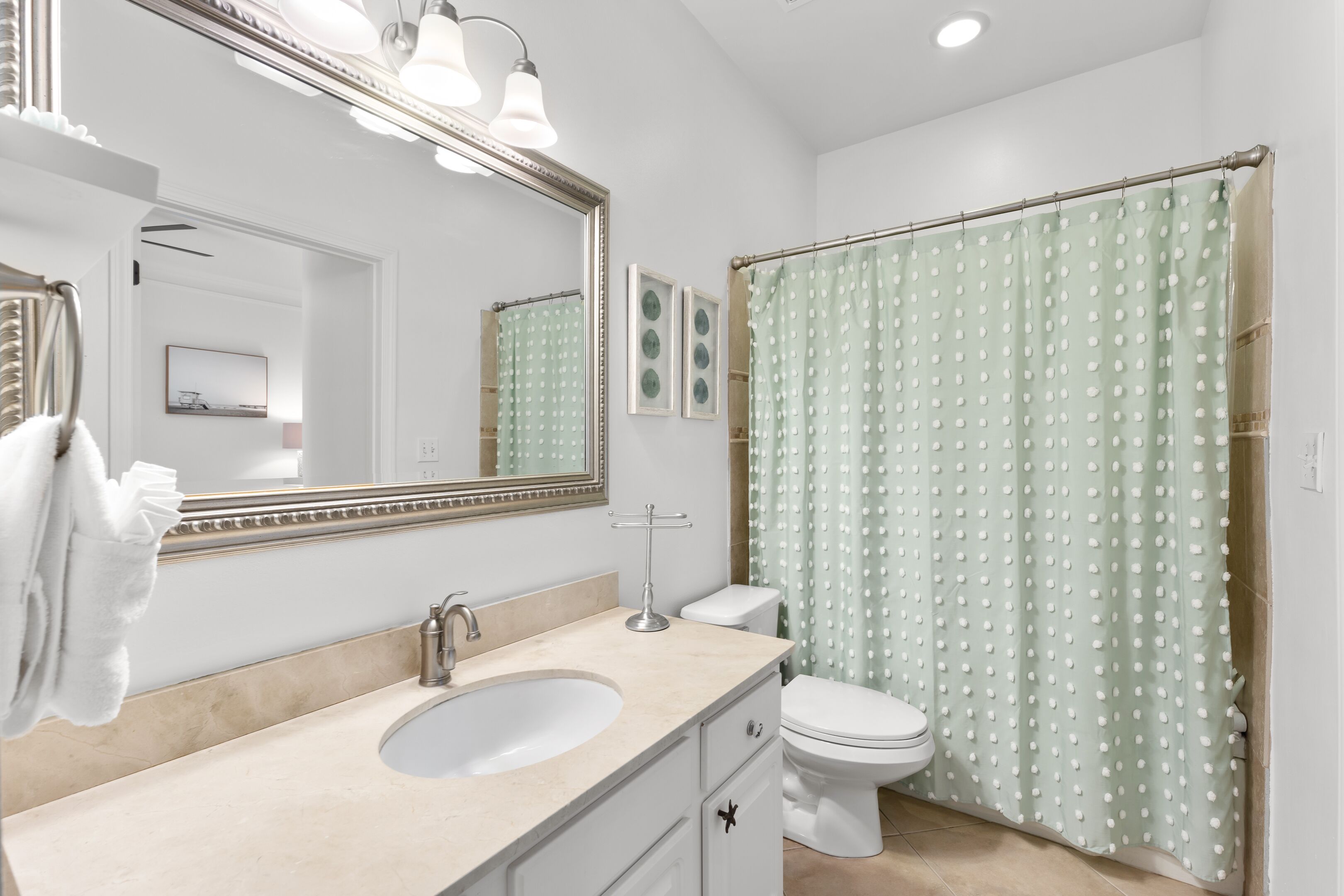 A bathroom with a sink, mirror, toilet, and shower curtain.