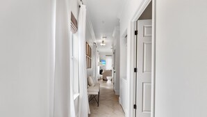 A narrow hallway with white walls and a tiled floor leading to a room with a white door. - Crystal Beach. Caribbean Dunes. Completely Renovated. Corner Unit. Gulf View.  (Destin)