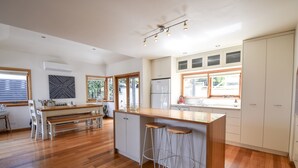 Eine moderne Küche mit einer Holz-Kochinsel, Barhocker und einem Essbereich mit einer Bank.