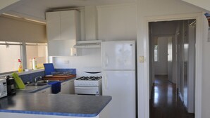 Eine kleine Küche mit Gaskochfeld, Kühlschrank und einer blauen Arbeitsplatte.