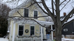 A two-story house with a porch, a wreath on the door, and a snow-covered yard. - Spacious home w/Hot Tub near Lake Superior walk to restaurants, breweries, beach (Marquette)