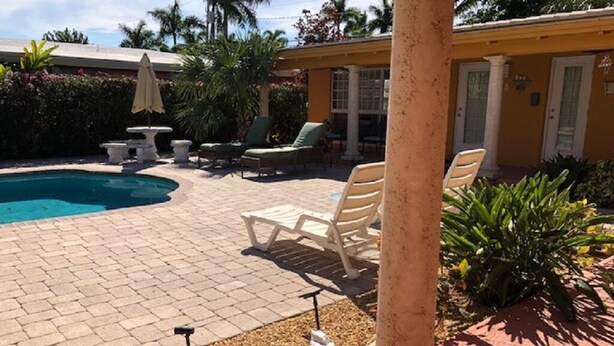 A pool area with lounge chairs, a table, and a small garden.