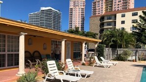 A pool area with sun loungers and a building with columns.