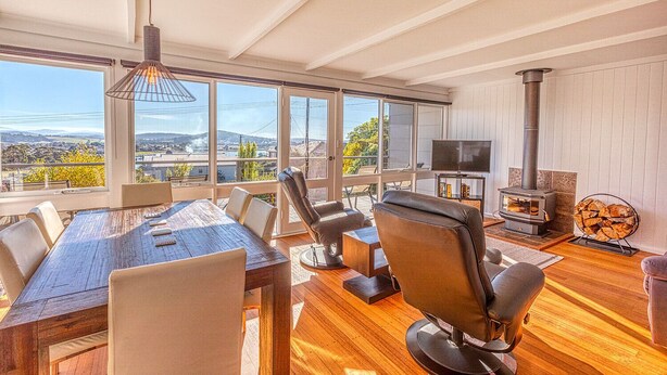Un salon spacieux avec une grande table en bois, des sièges confortables, une cheminée et un téléviseur.