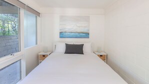 Une chambre à coucher avec un grand lit, deux tables de chevet, une fenêtre et un tableau au mur.