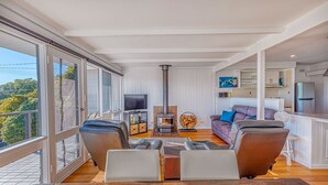 Un vaste espace de vie agrémenté d’une cheminée, de sièges confortables et d’une grande fenêtre donnant sur un paysage verdoyant.