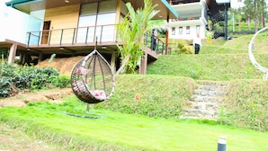 A modern building with a wooden facade, a balcony, and a hanging chair in the garden. - Aloft Grand Hotel (Kumbalwela)