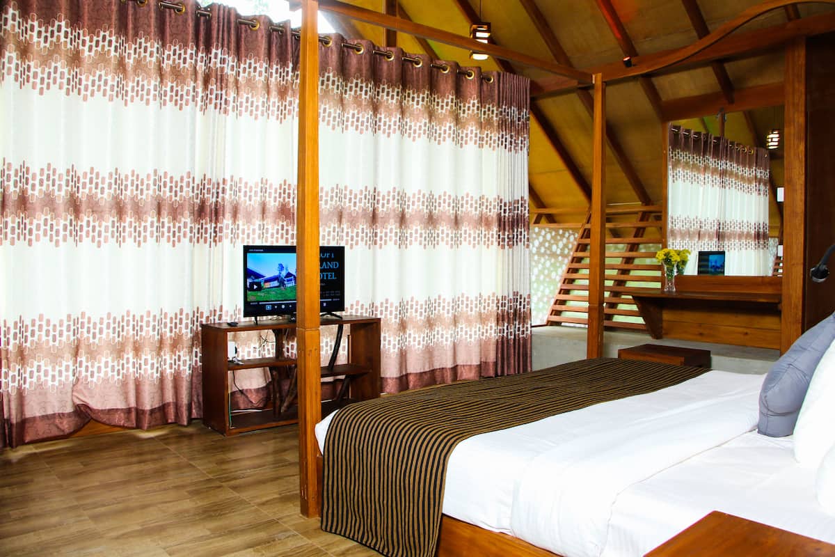 A bedroom with a bed, a desk with a computer, and curtains.