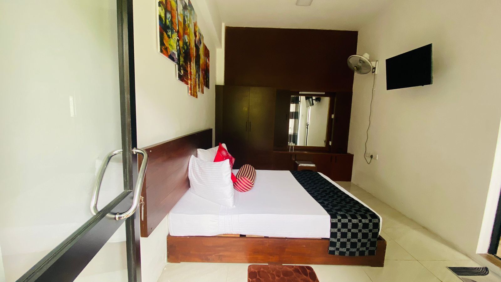 Une chambre d’hôtel avec un lit, une table de chevet, une télévision et un miroir.