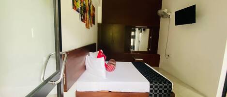 Une chambre d’hôtel avec un lit, une table de chevet, une télévision et un miroir.