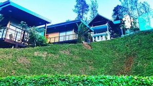 A modern building with multiple levels and balconies, surrounded by lush greenery and trees. - Aloft Grand Hotel (Kumbalwela)