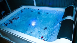 A hot tub with water, bubbles, and rose petals. - Aloft Grand Hotel (Kumbalwela)