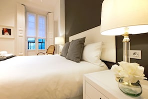 Una habitación de hotel con una cama grande, una mesita de noche con lámpara y una ventana con vistas.