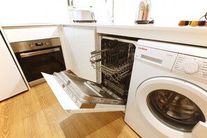 A compact kitchen with a dishwasher, an oven, and a washing machine.