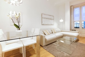 Una sala de estar moderna con una mesa de centro de vidrio, un sofá blanco y una mesa de comedor de vidrio.